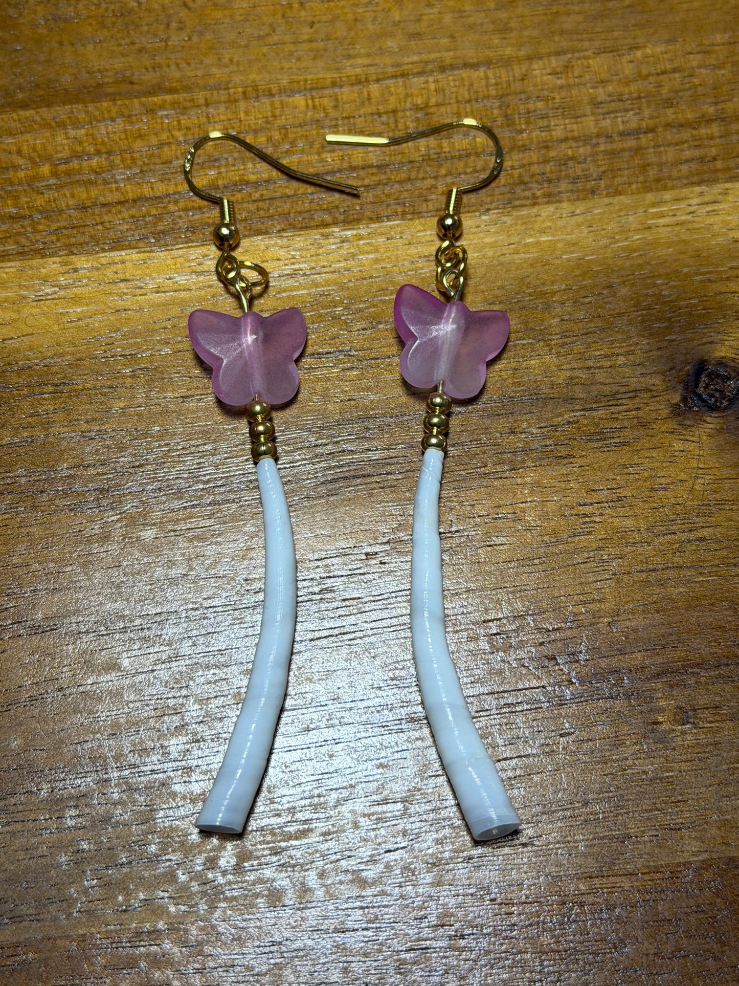 Pair of earrings with pink flower-shaped beads on a wooden surface